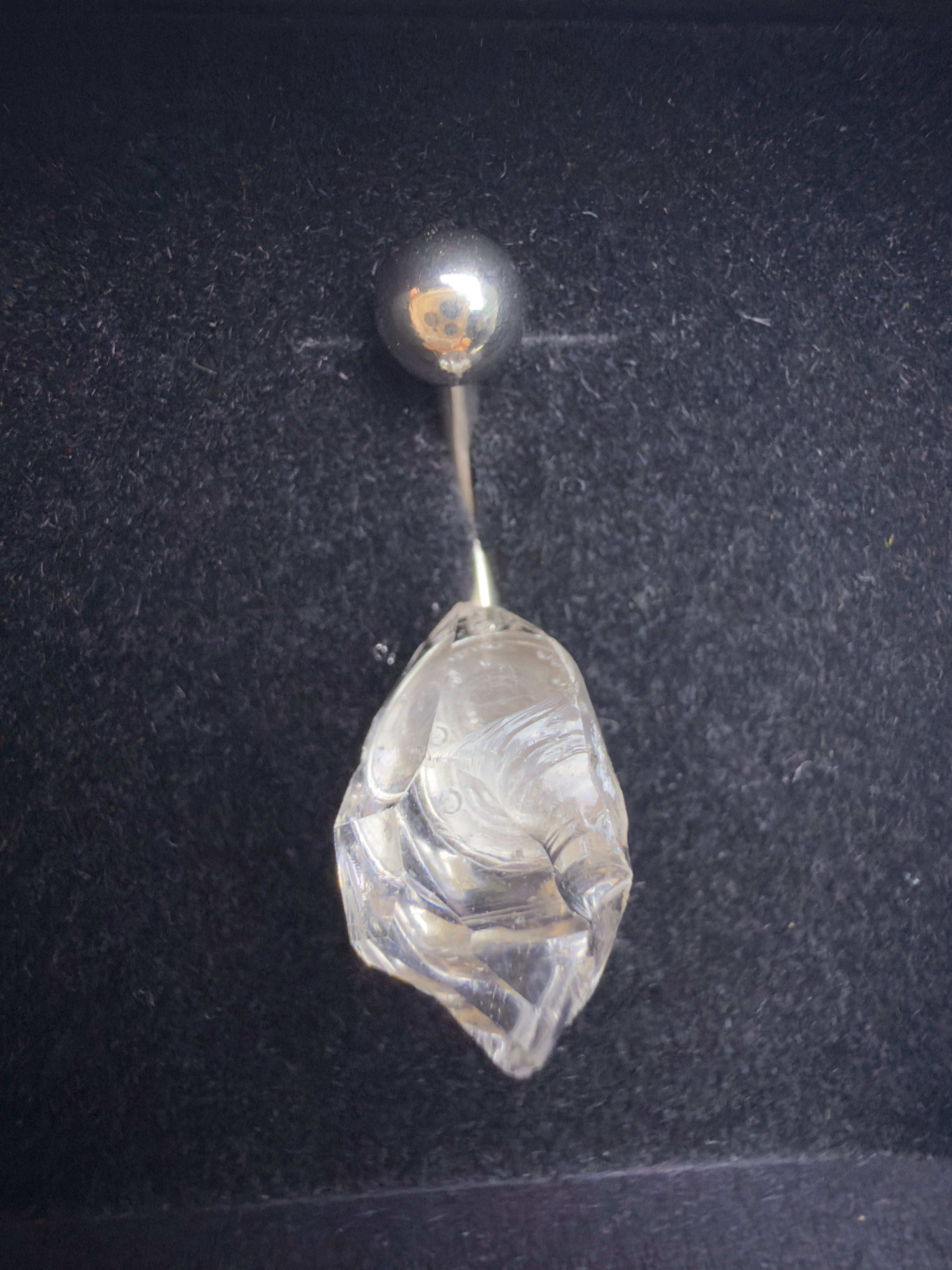 Belly button ring with a clear stone and silver ball on a dark background
