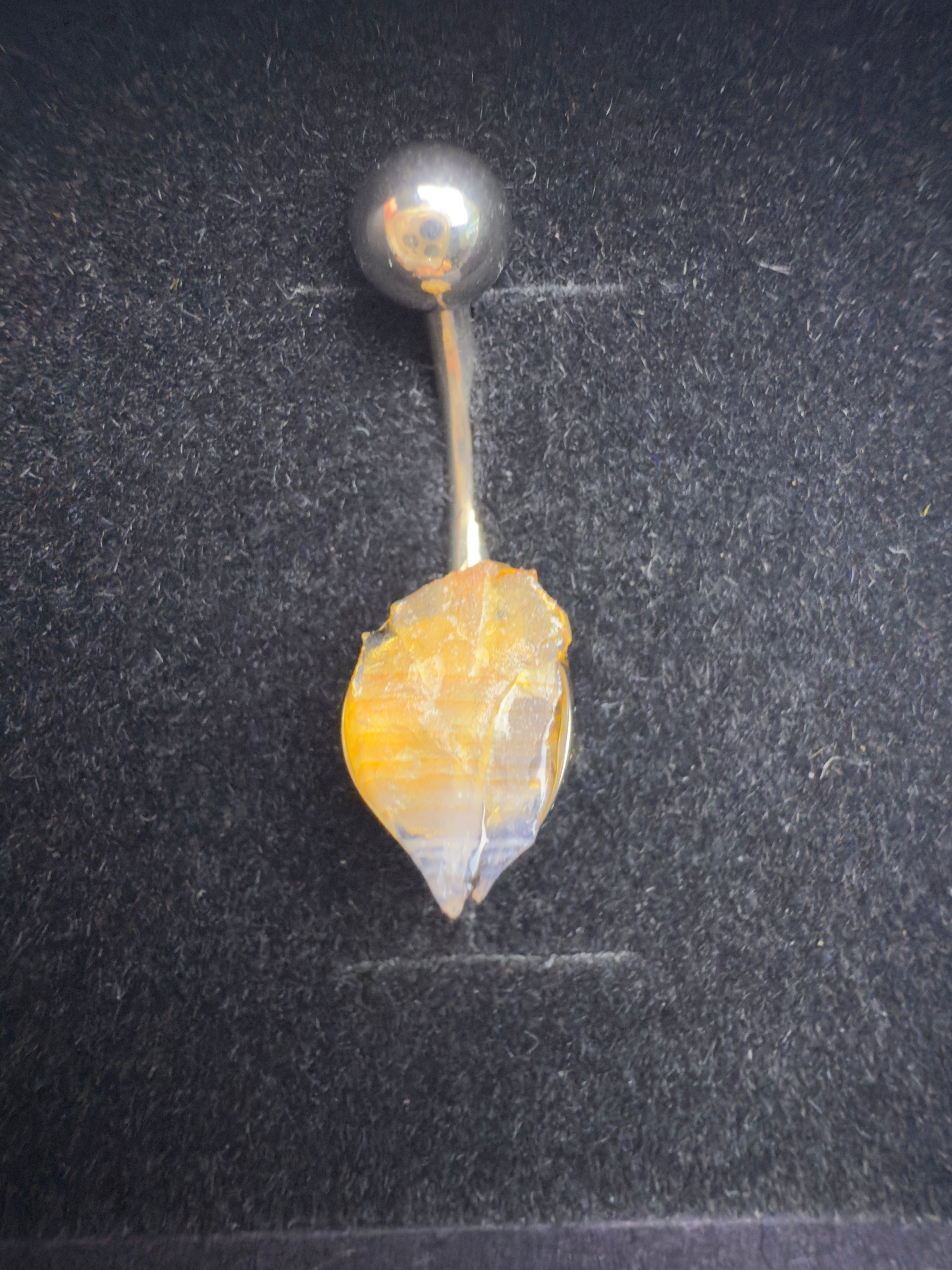 Belly button ring with a decorative stone on a dark background